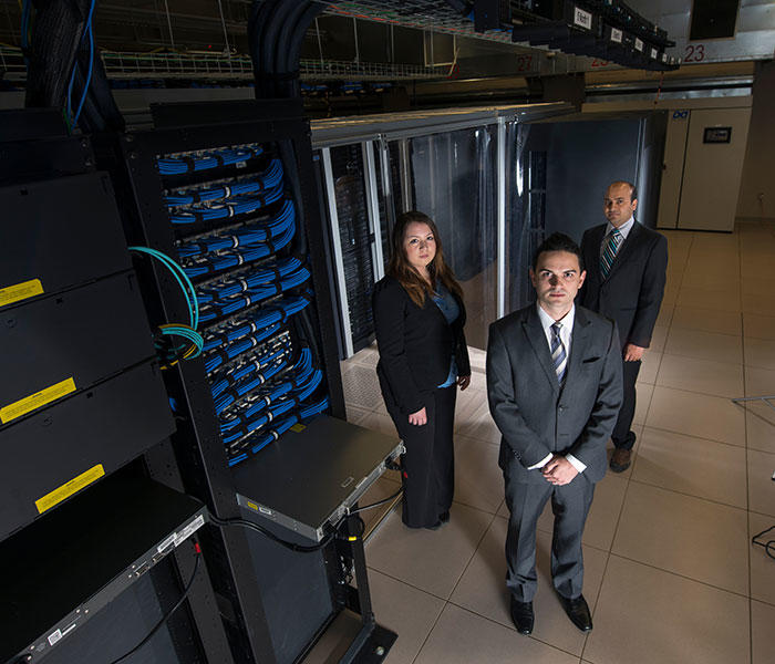 Three students standing in a massive computer room.